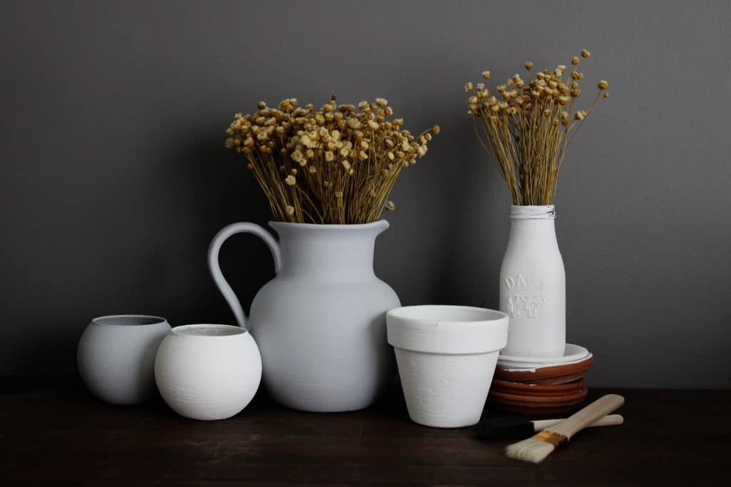 faux ceramic projects are lined up on display with dried florals