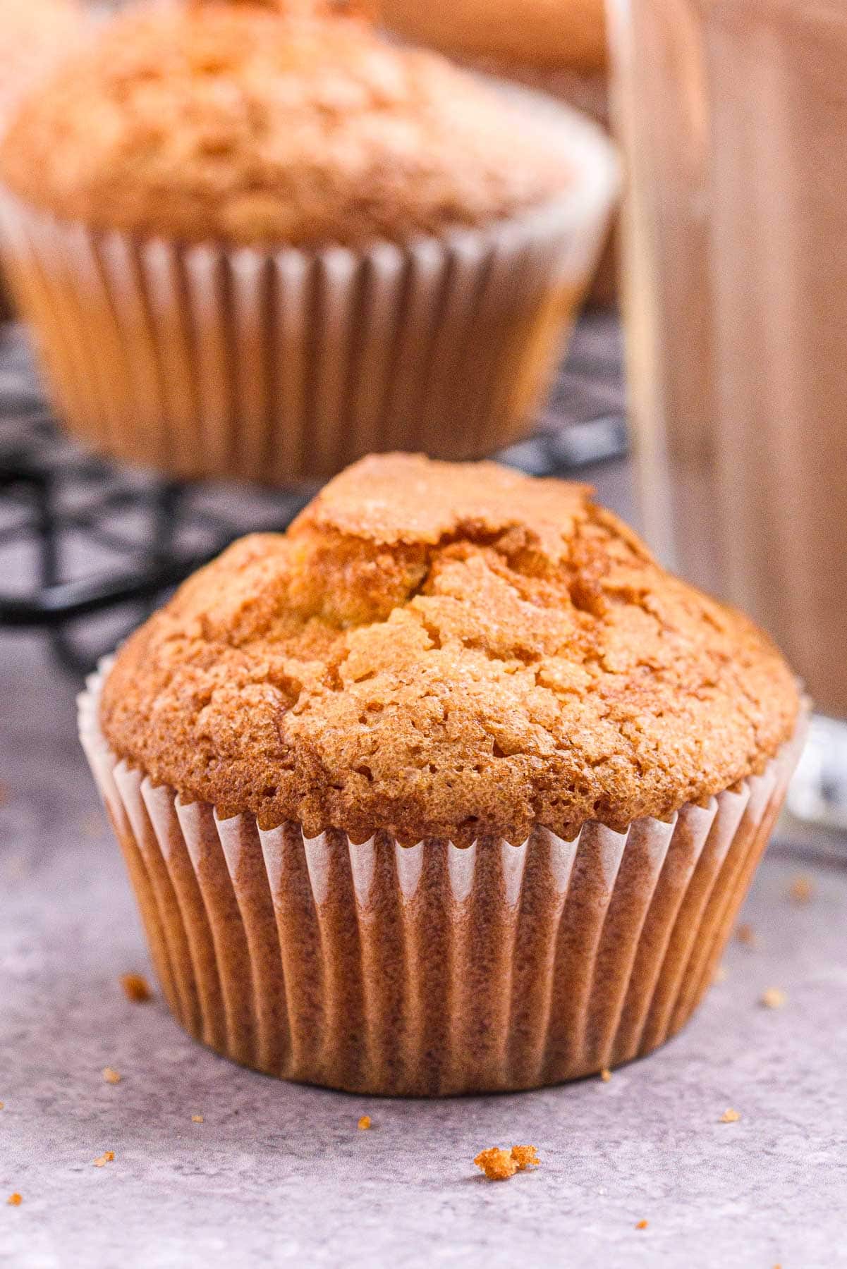 close up shot of a spanish muffin with one muffin behind and chocolate milk beside.